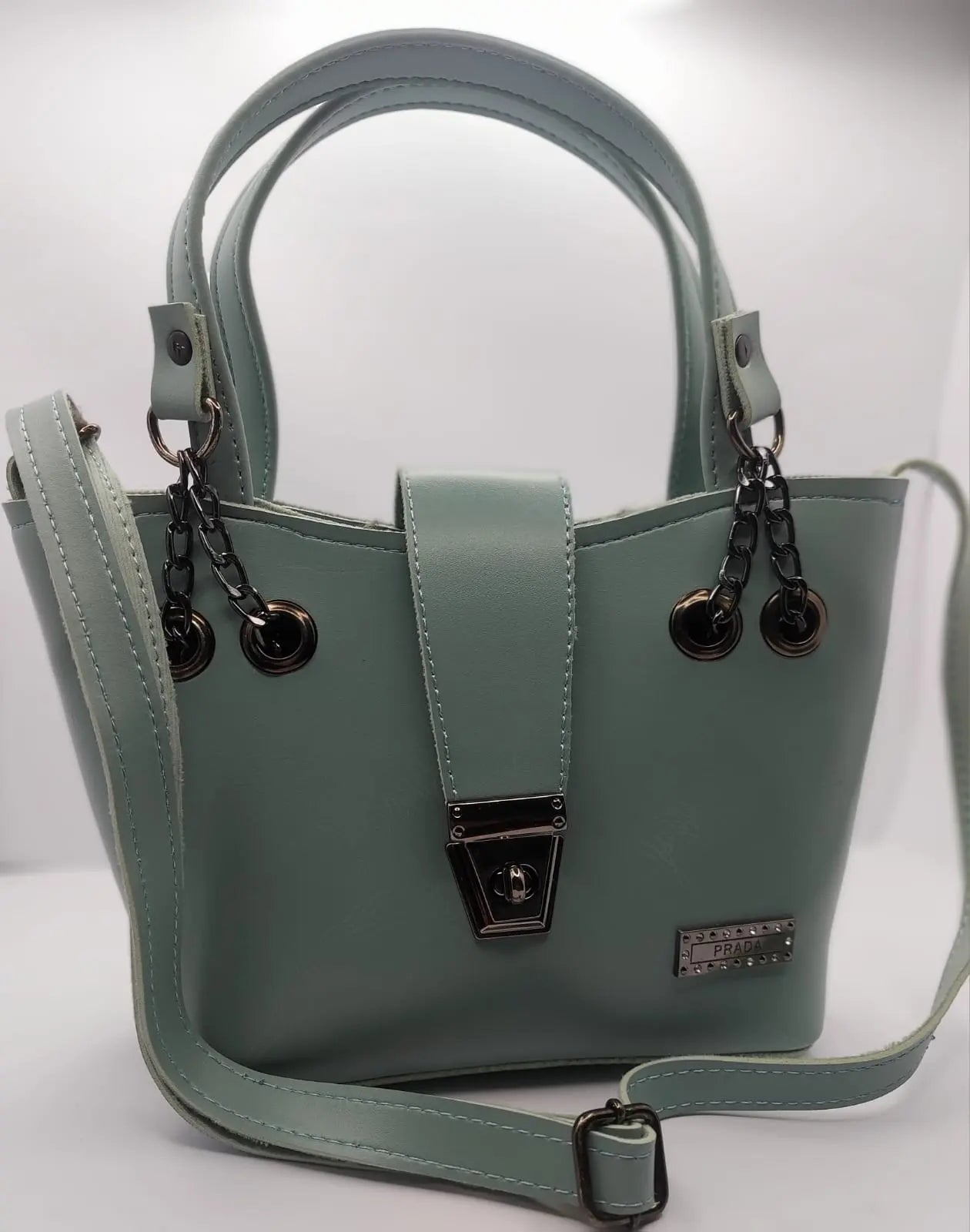 Mint Green tote bag with metallic twisted lock, crafted from premium PU leather. Features hand tote and adjustable shoulder straps, dual zippers fot storage, and a sleek solid design with metallic details. Ideal for daily use or special occasions