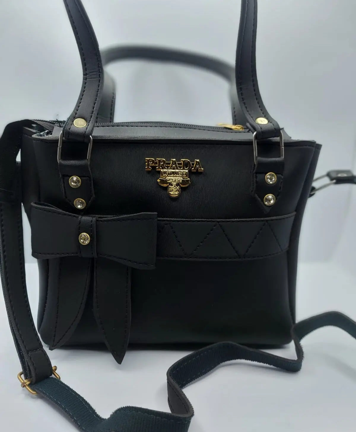 Luxurious camel brown tote bag with a silk-textured finish, featuring a bow charm accent and a gold-tone Prada-inspired logo, designed with dual carrying options for versatility and sophistication