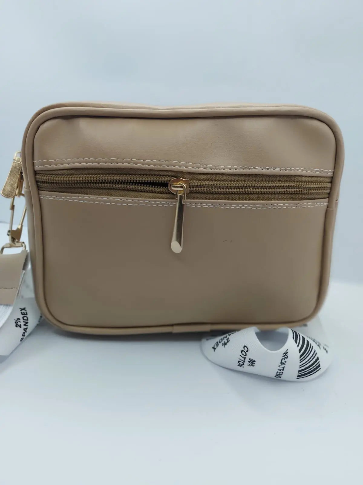 Beige Urban Grace Crossbody Bag with quilted design, gold-tone logo, and adjustable black-and-white strap. Stylish and functional for daily use