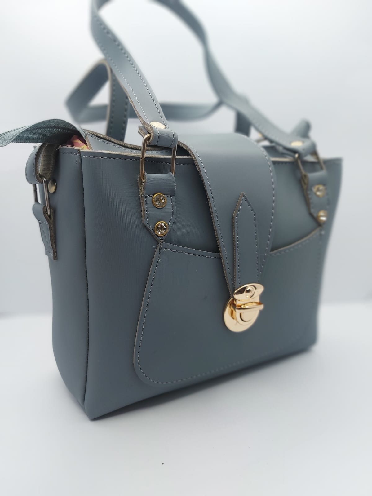 Stylish slate gray tote bag with a gold-tone lock, front pocket, and dual carrying options. Made of high-quality synthetic leather with neat stitching