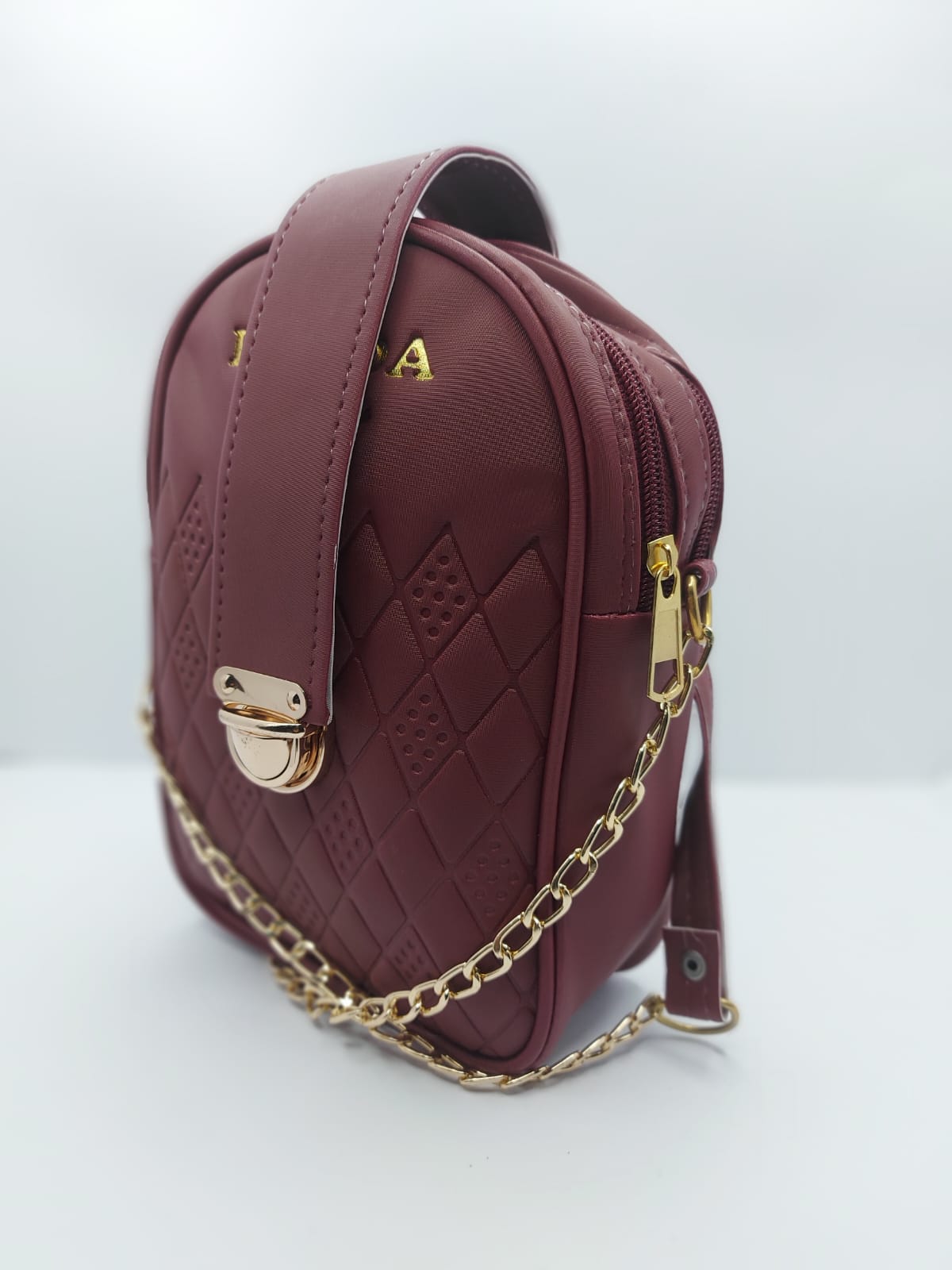 Compact Maroon Crossbody with secure strap lock and leather shoulder pad, perfect for essentials and a chic everyday style.
