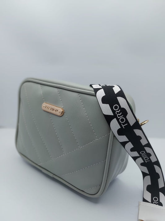 Light Grey Urban Grace Crossbody Bag with quilted design, gold-tone logo, and adjustable black-and-white strap. Stylish and functional for daily use
