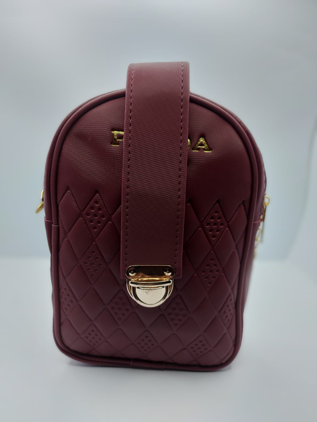 Compact Maroon Crossbody with secure strap lock and leather shoulder pad, perfect for essentials and a chic everyday style.
