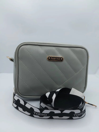 Chic light grey quilted crossbody bag with a gold-tone logo plate and a trendy adjustable strap for a modern everyday look.
