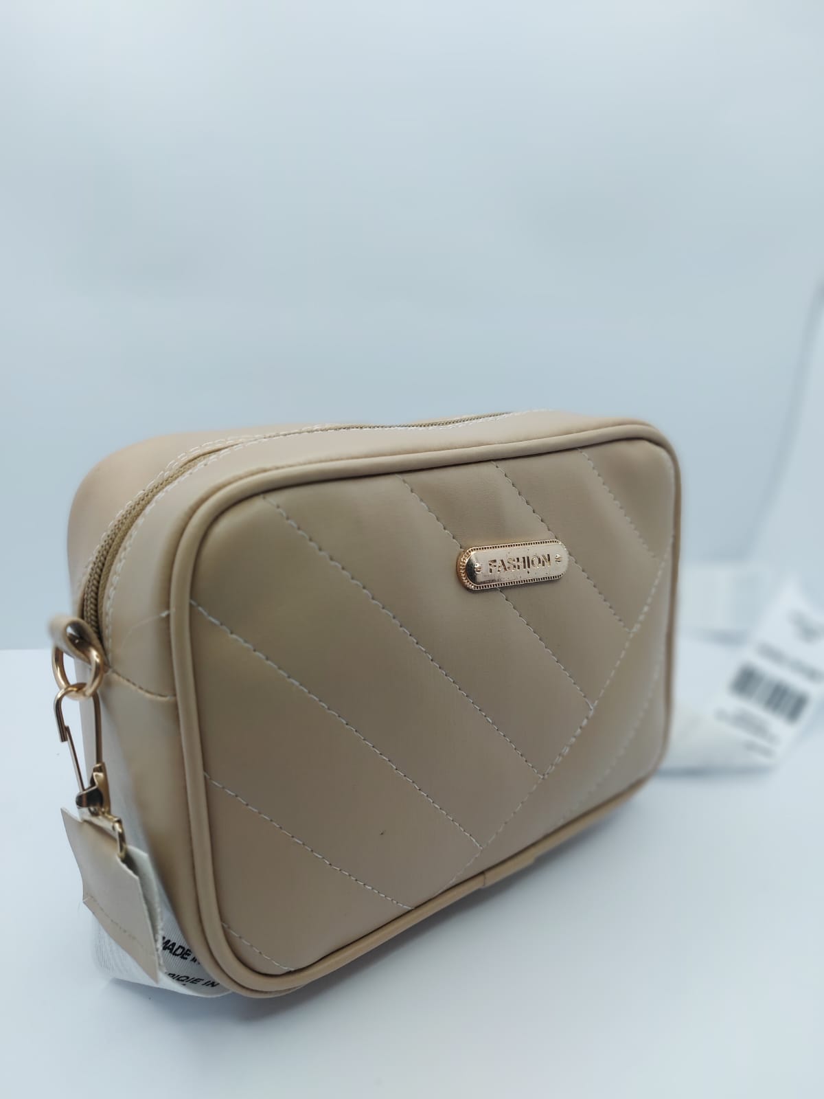 Beige Urban Grace Crossbody Bag with quilted design, gold-tone logo, and adjustable black-and-white strap. Stylish and functional for daily use